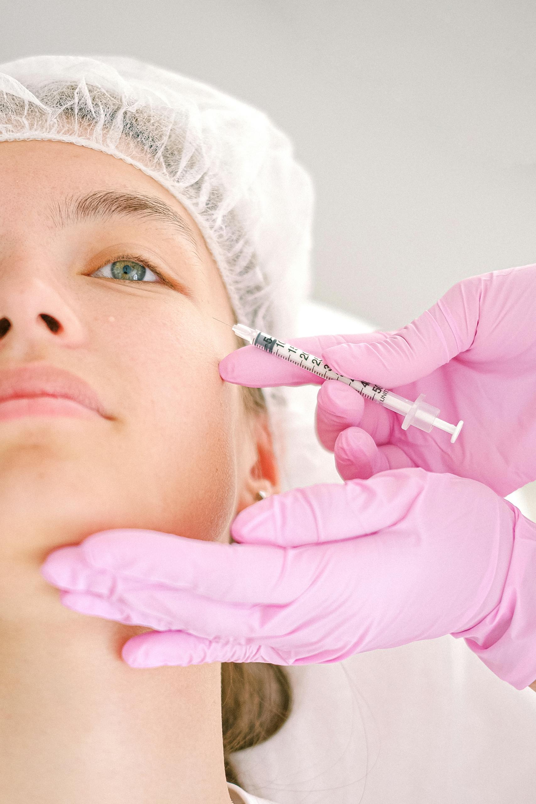 Close-up of a beautician administering facial injection treatment to a woman in a clinical setting.