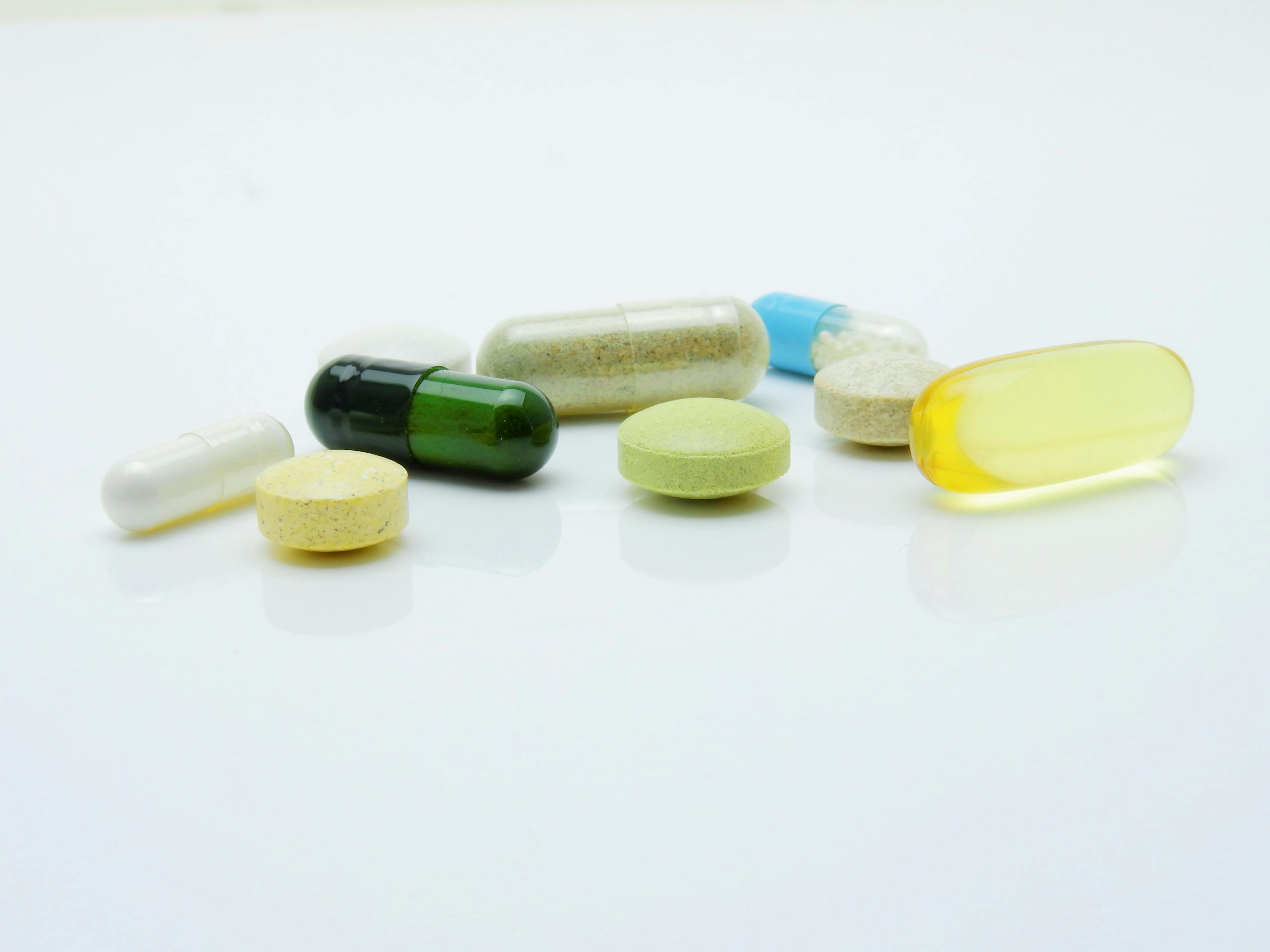 Close-up of various pills and capsules arranged on a white surface, representing healthcare and medicine.